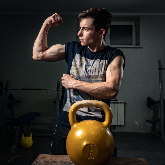 Pratiquant musclé après suivi coaching prise de masse en salle sombre