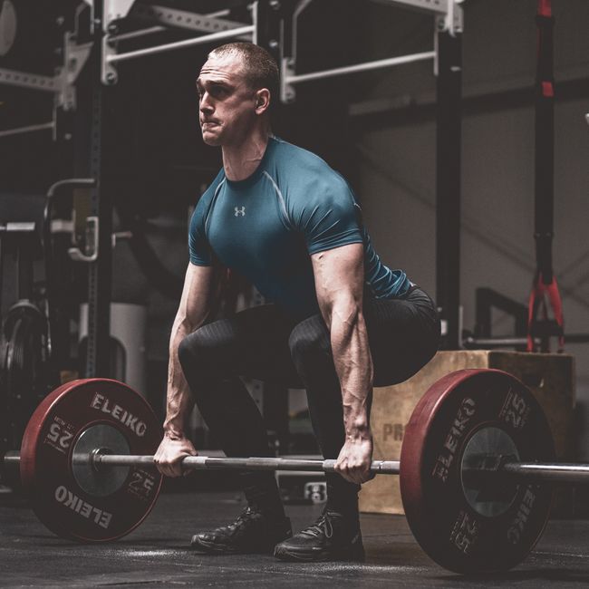 Barre chargée de disques dans une salle de musculation sombre avec lumière dure