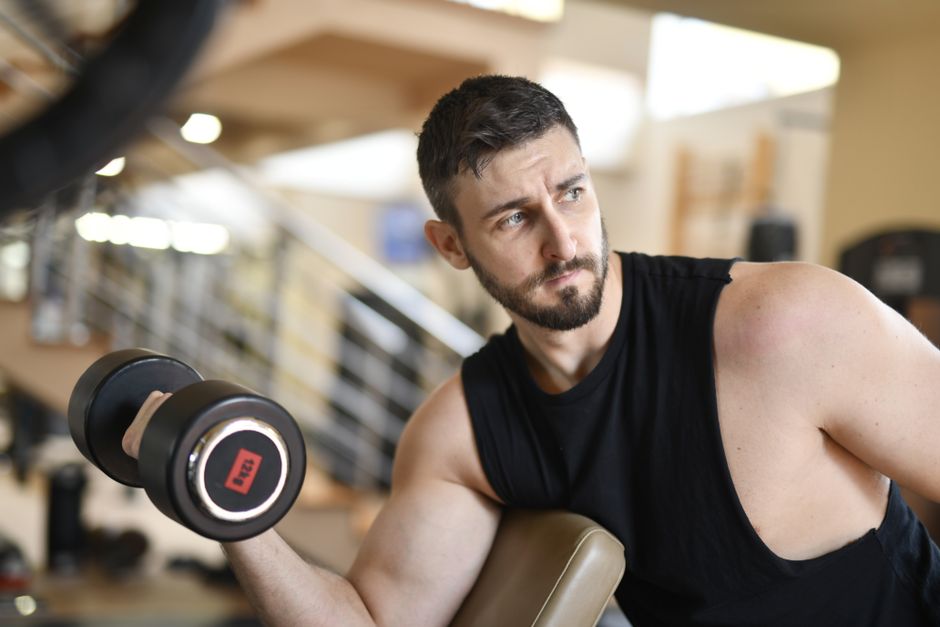 Homme musclé racontant son suivi coaching devant la caméra en salle sombre
